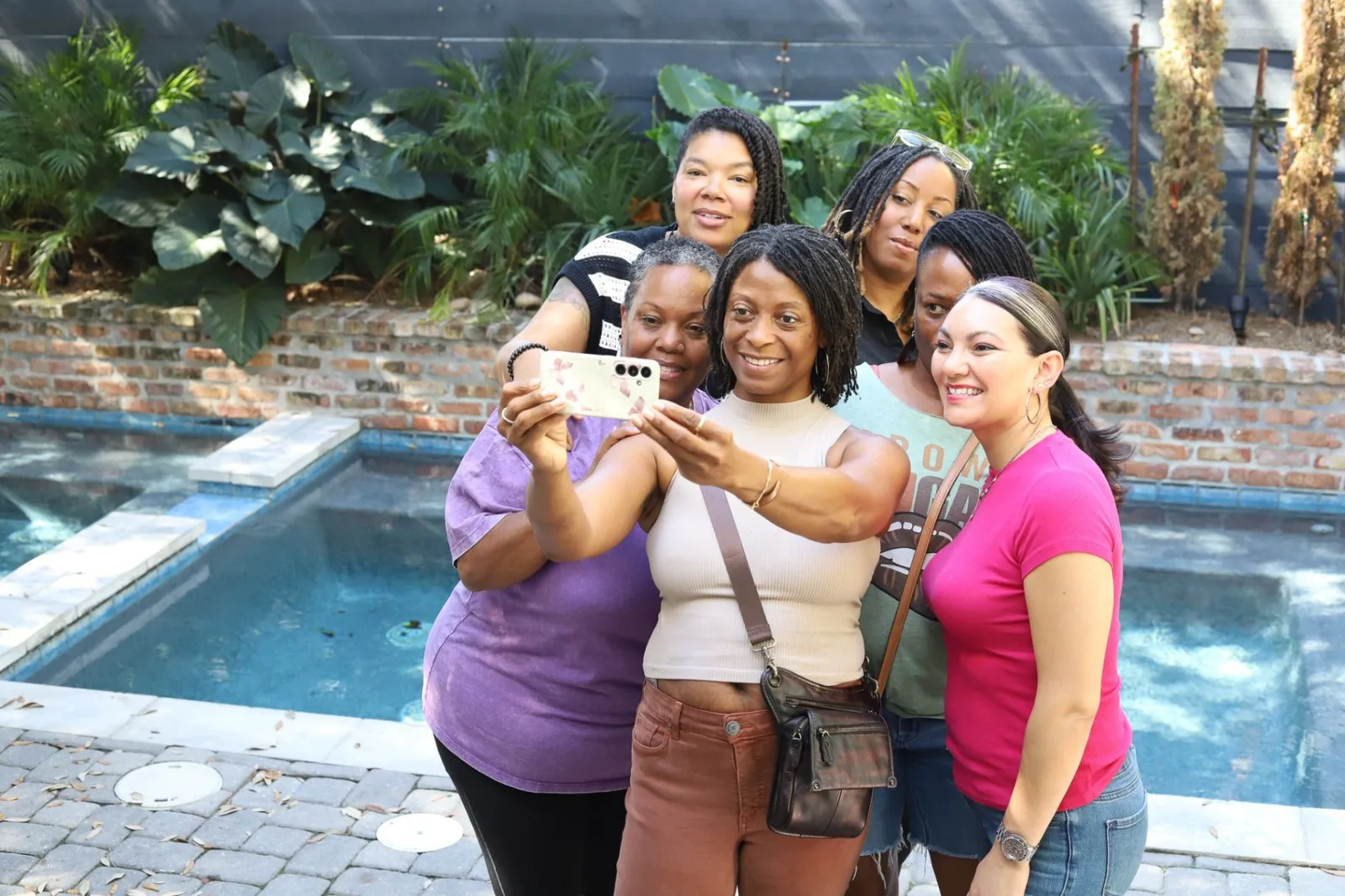 Women posing together for a photo by the pool in the courtyard