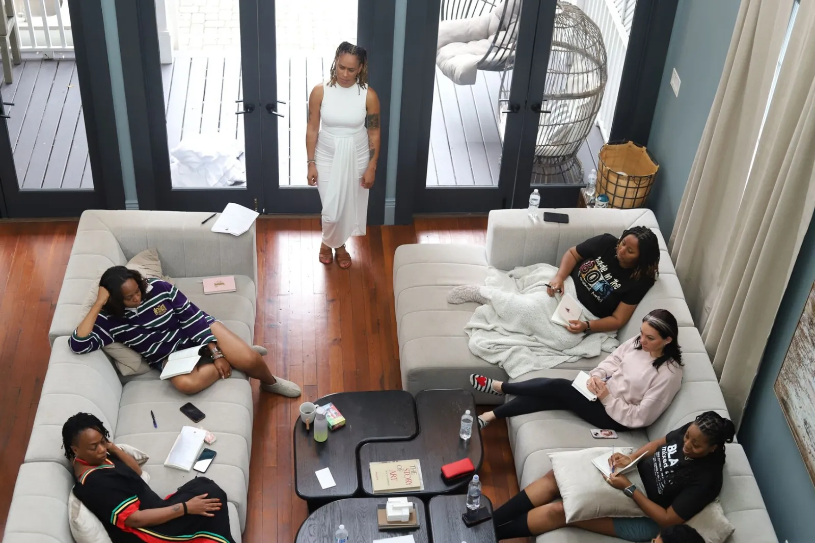 Overhead view of the retreat room with Siobhan Middleton standing as the women write in their journals on the sofas